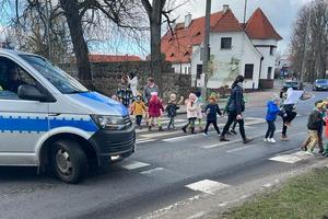 policyjny radiowóz stoi przy przejściu dla pieszych przez które przechodzą dzieci