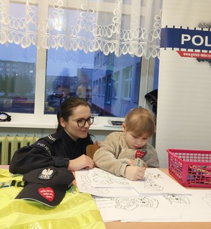Policjantka maluje kolorowankę z dzieckiem.