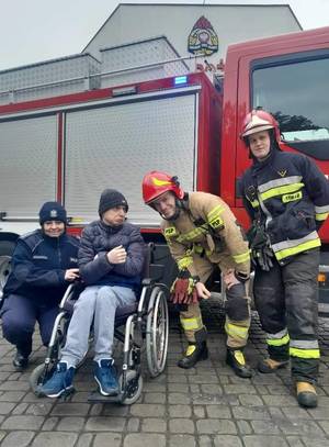 Dzielnicowa wspólnie z funkcjonariuszami straży pożarnej i z niepełnosprawną osobą.