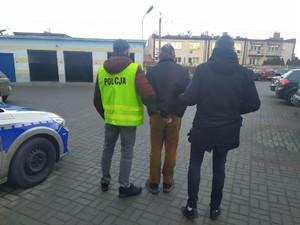 policjanci prowadzą zatrzymanego mężczyznę