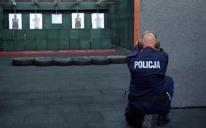 Policjant strzela zza zasłony do tarczy na strzelnicy