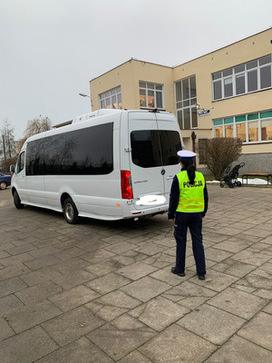 Umundurowany policjant stoi przy autokarze.