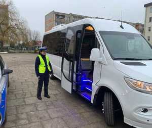 Umundurowany policjant stoi przy autokarze.