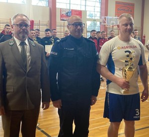 Umundurowany policjant stoi, obok niego umundurowany mężczyzna oraz mężczyzna ubrany na sportowo.