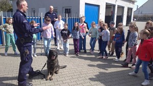 Policjant stoi, dzieci stoja obok niego.