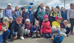 Dzieci stoją, umundurowany policjant z psem kuca , zdjęcie grupowe.