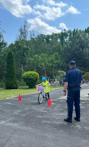 Umundurowany policjant stoi. dziecko jest na rowerze.