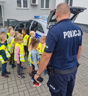 Umundurowany policjant stoi, obok stoją dzieci.