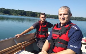 Umundurowany policjant siedzi w łódce, obok siedzi inna osoba.