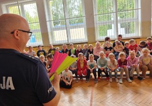 Umundurowany policjant stoi, obok niego są dzieci.