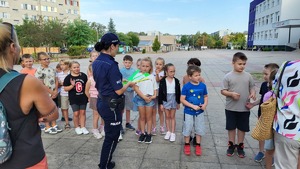 Policjantka rozdaje dzieciom opaski odblaskowe.