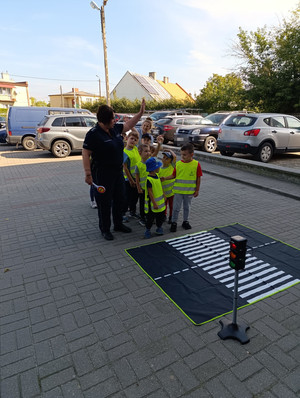 [Policjanci uczą dzieci przechodzenia przez pasy.