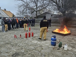 Ewakuowani pracownicy i policjanci stoją w miejscu zbiórki