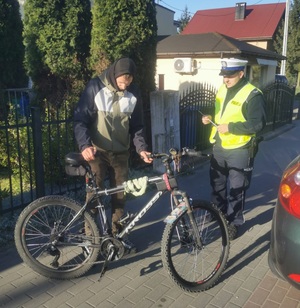 Policjant wręcza rowerzyście odblask